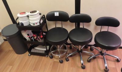Plusieurs tabourets et chaises noirs sont alignés contre un mur