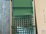 a green cage with a bird inside of it on the ground