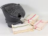 une petite théière noire, avec des serviettes et un torchon posés sur la table