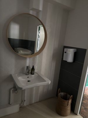 une salle de bains équipée d'un lavabo, d'un miroir et d'un distributeur de serviettes