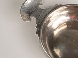 a silver spoon with a handle on a white surface