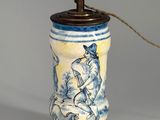 a blue and white vase with a lamp on top of it