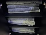 towels are stacked on a shelf in a bathroom next to a sink