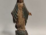 statue d'une femme tenant une croix, posée sur un socle en bois