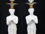 pair of white marble statues holding a vase on top of each other