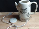 a white tea pot with a mouse attached to it