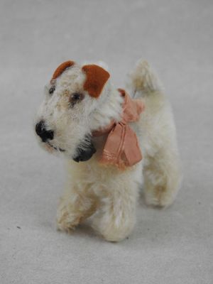 un petit chien blanc et marron avec un nœud rose autour du cou