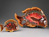 two small ceramic fish figurines on a stand on a gray surface