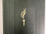 an open book with a gold flame on it sitting on a table
