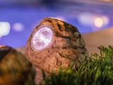 un rocher surmonté d'une lampe, près d'une piscine