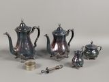 a silver tea set on a table with a cup and spoon