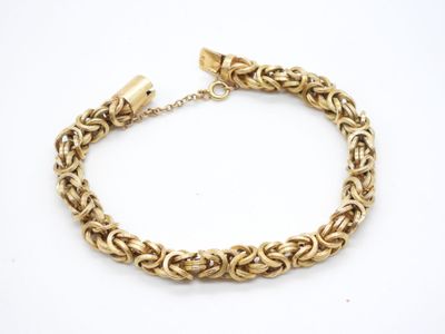 un bracelet à chaîne en or avec un fermoir sur fond blanc