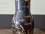 a black vase with gold designs on it on a wooden table