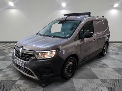La camionnette grise est garée sur un sol carrelé à damier.