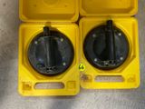 deux boîtes en plastique jaunes avec des couvercles noirs et des poignées, posées par terre