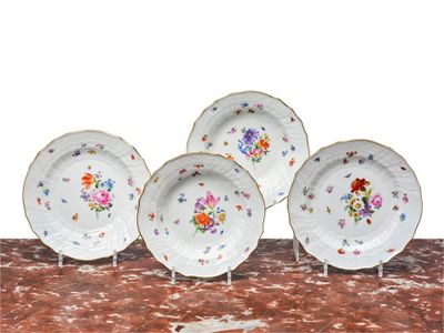 four plates with flowers on them are sitting on a table