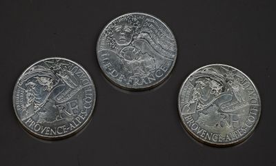 trois pièces d'argent posées les unes à côté des autres sur une surface noire
