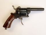 un vieux revolver avec une poignée en bois sur une surface blanche