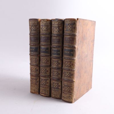 trois vieux livres sont empilés sur une surface blanche