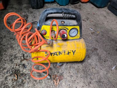 a yellow air compressor sitting on the ground next to other equipment