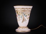 a white vase with gold trim and a chain on a black background