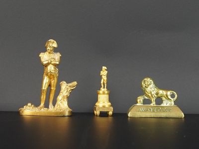 trois figurines en or représentant un homme et un chien, posées sur une table