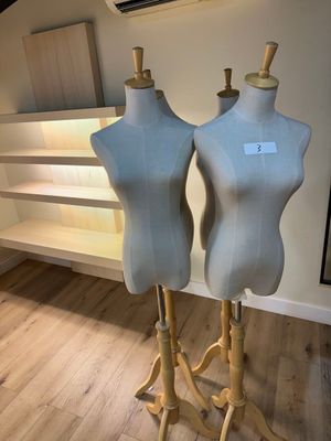 two mannequins sitting on a stand in a room