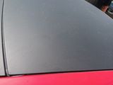 a man standing next to a red car in a parking lot