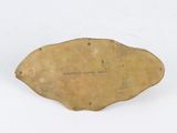 an old brass plate with writing on it sitting on a white surface