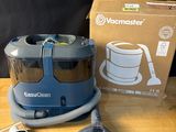 L'aspirateur est posé sur la table, à côté de la boîte.