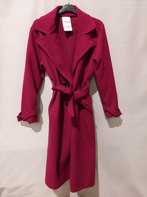 a red coat is hanging on a hanger on a white wall