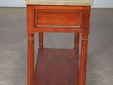 an old wooden table with a marble top and a magazine rack