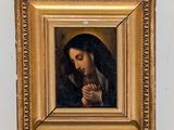painting of a woman praying in a gold frame on a white wall