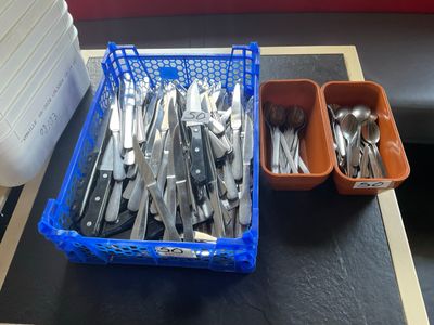 un panier contenant des couverts posé sur une table à côté d'un récipient contenant des couverts