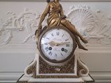 une horloge en or avec une femme assise dessus