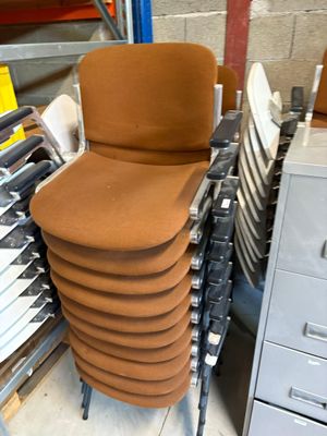 de nombreuses chaises empilées les unes sur les autres dans un entrepôt