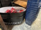 a bucket full of red and white lollipops next to a stack of blue plastic cups