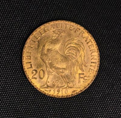 une pièce d'or sur laquelle est représenté un coq, posée sur un tissu noir
