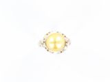une bague en perle jaune et diamants sur fond blanc
