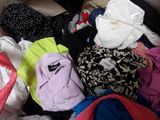 a pile of clothes that is sitting on a bed