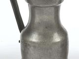 a silver pitcher with a handle on a white surface