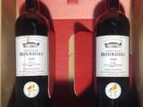 two bottles of red wine in a red box on a table