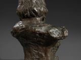 a bronze bust of a boy with his hands on his chest