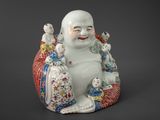 a figurine of a laughing buddha sitting on a cushion