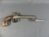 un petit pistolet avec une crosse en bois posé sur une table