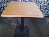 a wooden table with a metal base in front of a wall