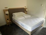 a bed with white sheets and pillows in a small room