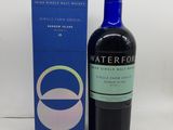 La bouteille se trouve à côté de la boîte de whisky single malt Waterford.