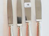 four knives are lined up in a row on a white surface