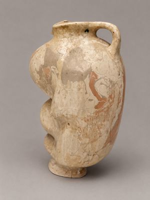un vieux vase orné d'un visage sur un fond gris